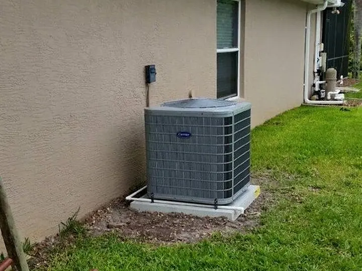 New condenser installed on a pad beside a stucco home