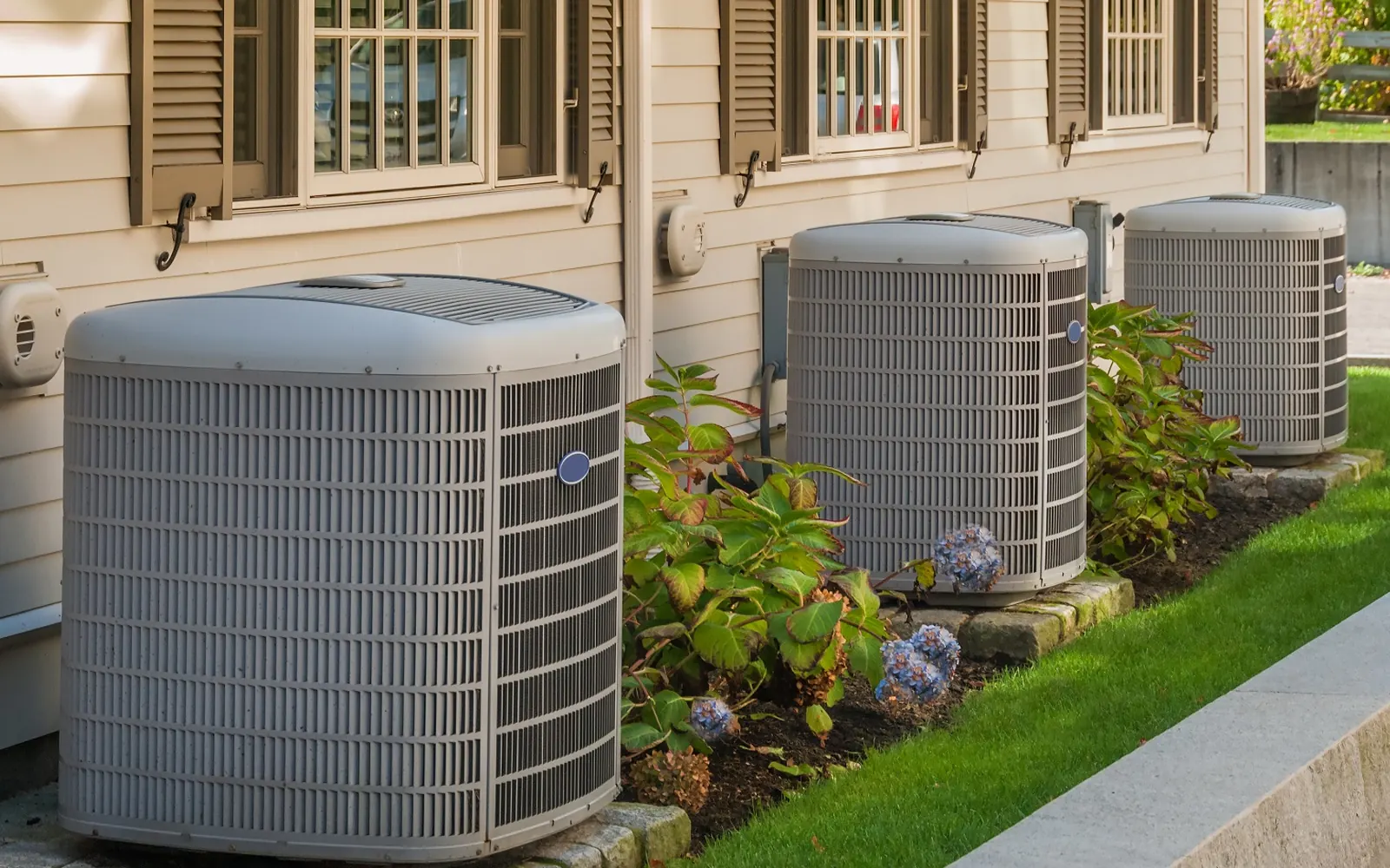 Two condensers beside a house with hydrangeas in bloom