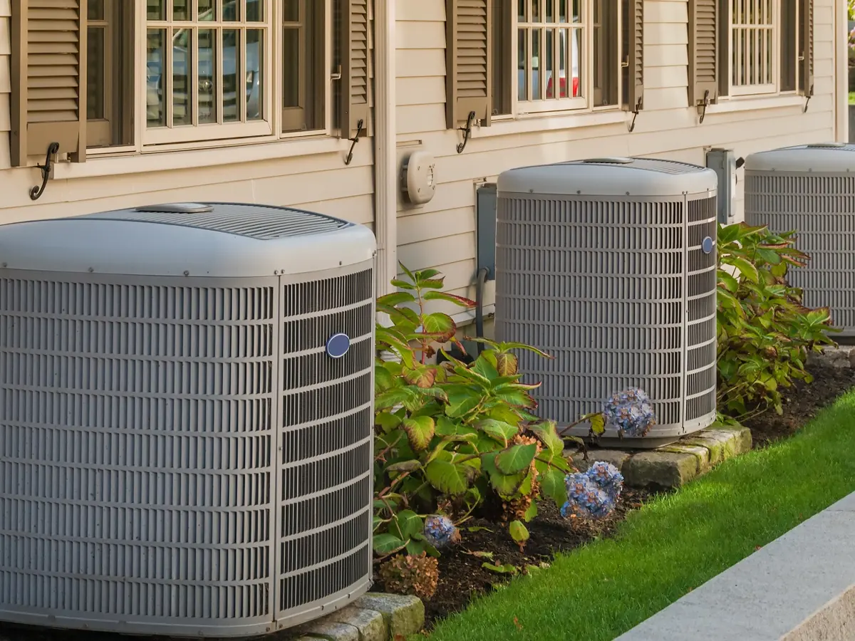 Two condensers beside a home with hydrangeas