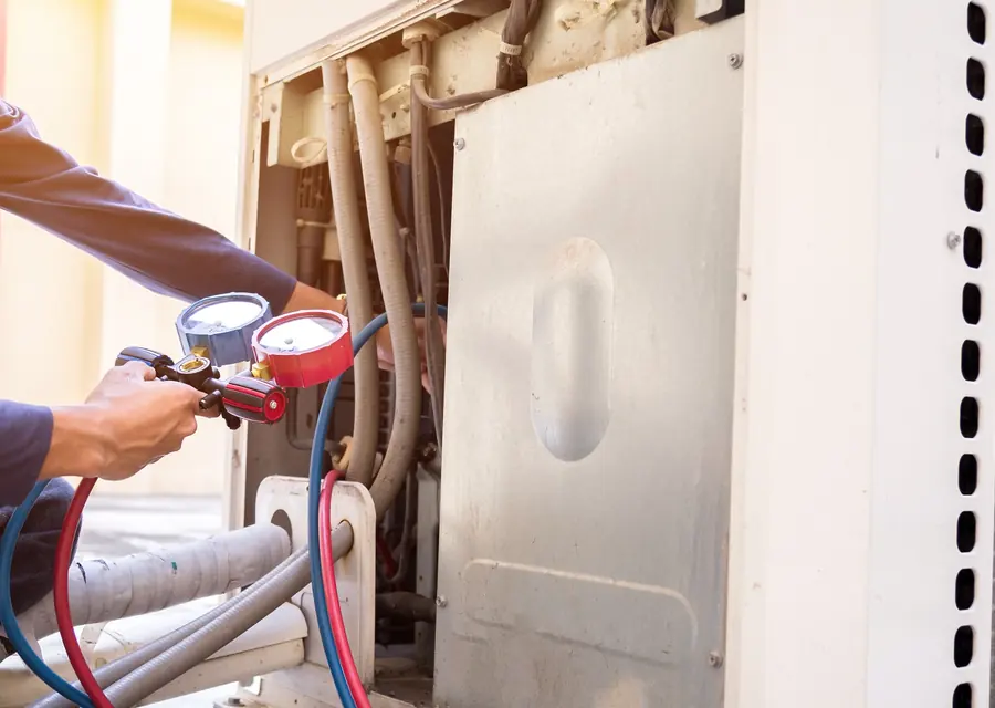 Technician checking gauges on a residential air conditioning unit